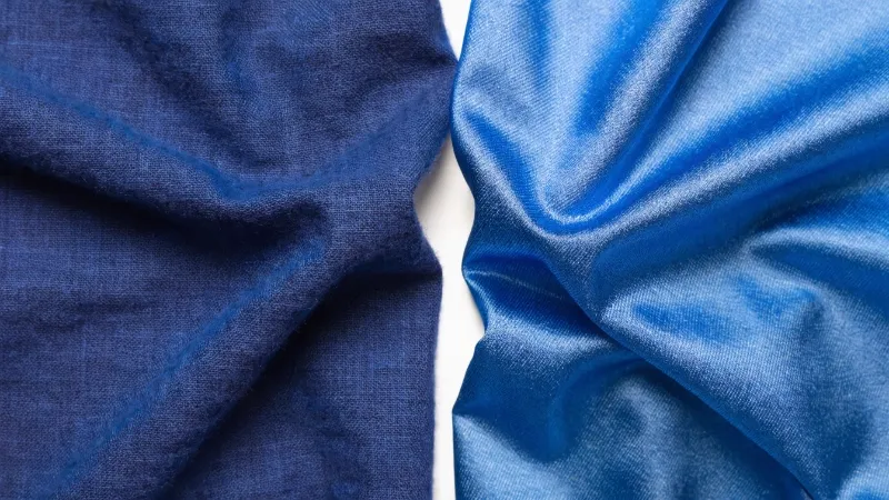 A close-up of cotton fabric next to polyester fabric