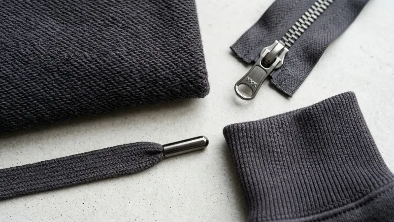 A close-up shot of hoodie fabric texture, a zipper, and a drawstring